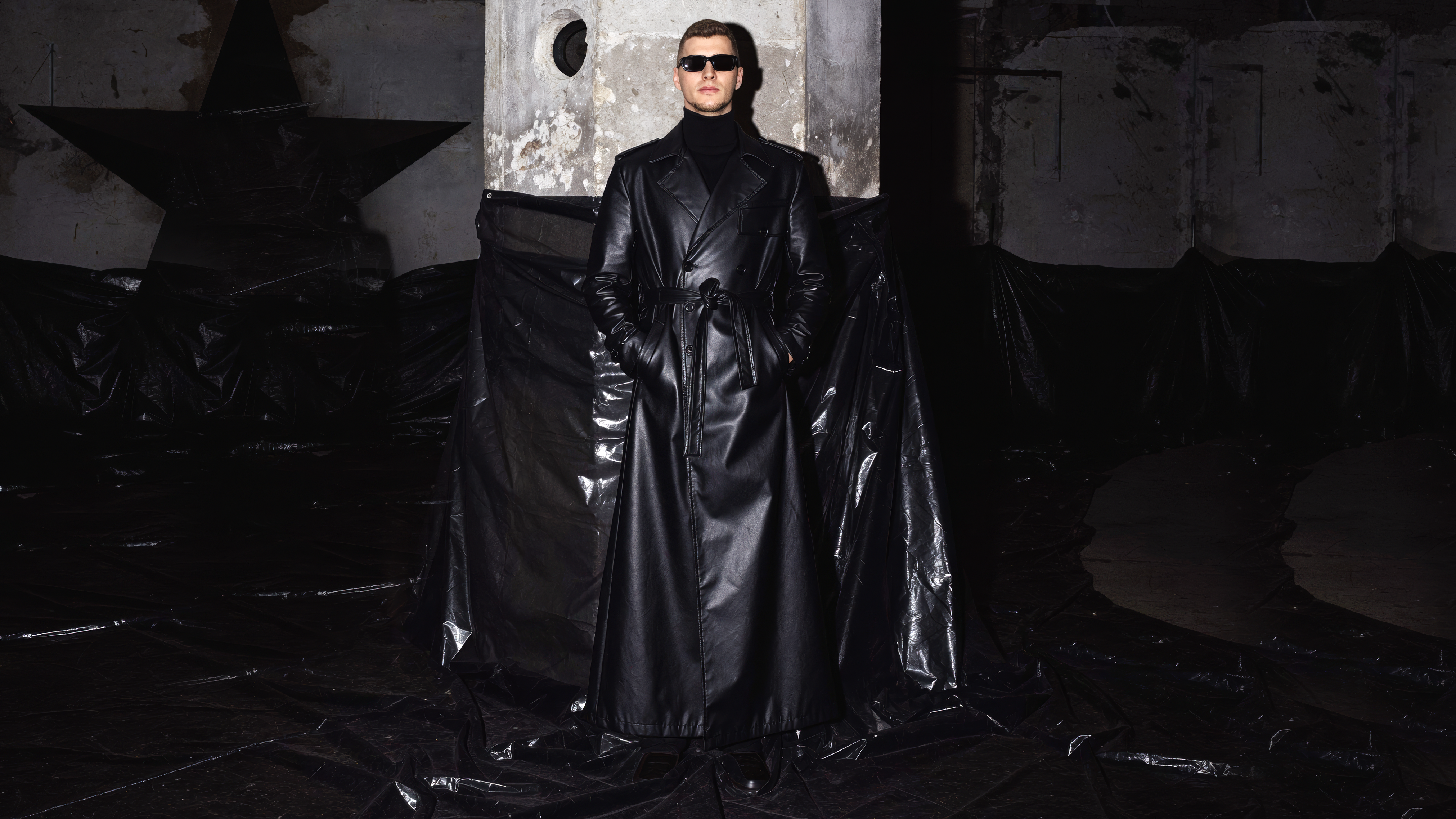 Ëlorian in a black leather silhouette within a raw architectural interior